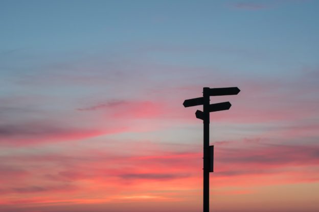 A road sign against a sunset sky.