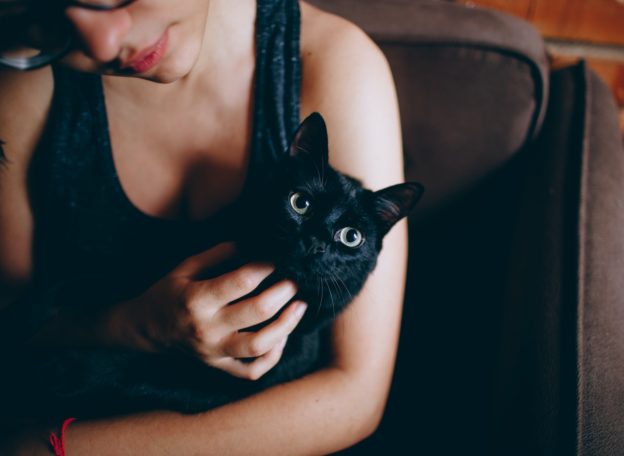 A woman holding a black cat