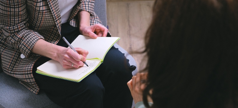a person writing in a notebook during the session of rebt for addiction