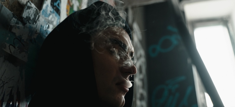 young man waiting in a building and smoking