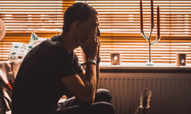 man sitting on the sofa with his hands on his face