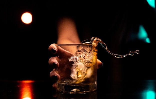 Person hold a glass of whiskey.