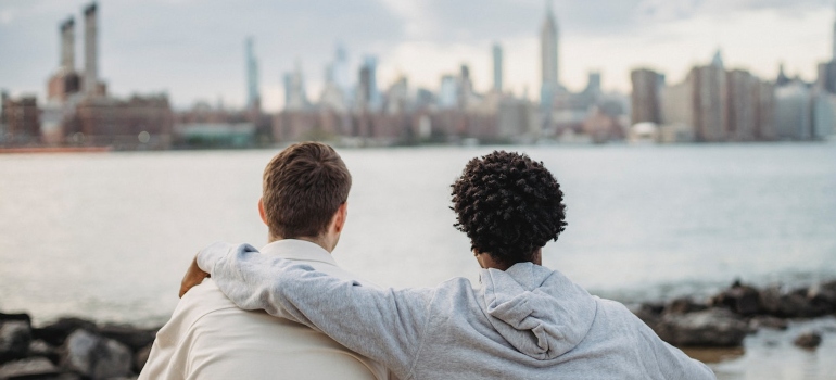 two friends enjoying a beautiful view and one is hugging the other to Support a Friend in Recovery