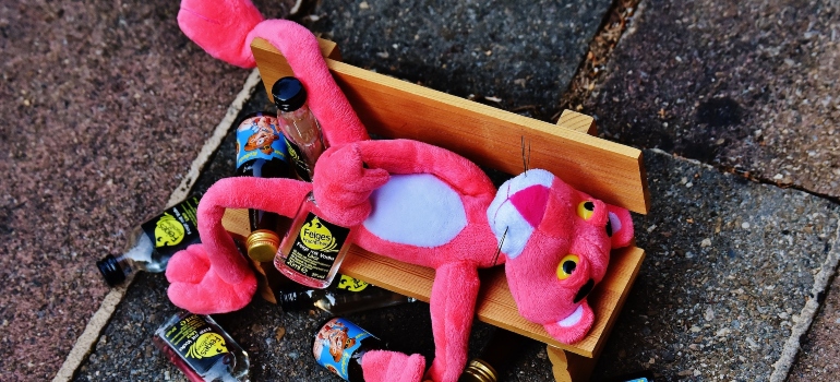 drunk pink panther on a toy bench holding bottles of whiskey representing signs to look for rehab in WV for your alcohol addiction