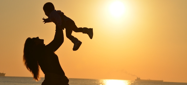 silhouettes of a happy mother carrying her kid