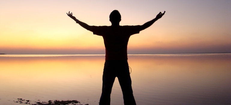 happy man enjoying the sunset when traveling while in recovery