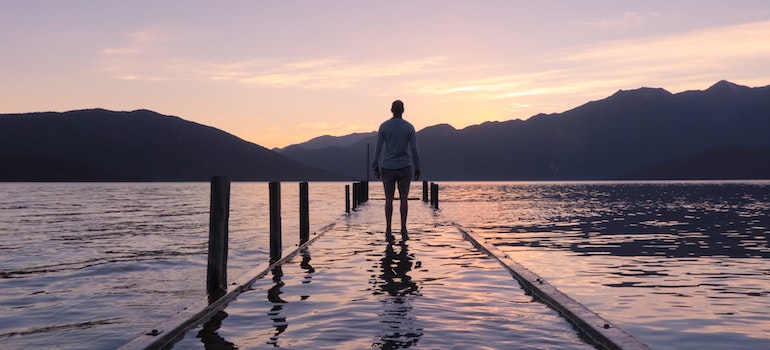 A man walking on a pier covered in water wondering how small steps make big changes during recovery