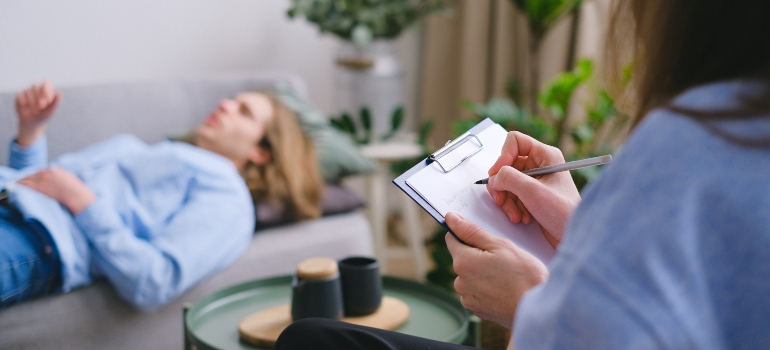 a therapist person taking notes while their patient is lying on a couch and talking about anger issued during addiction treatment