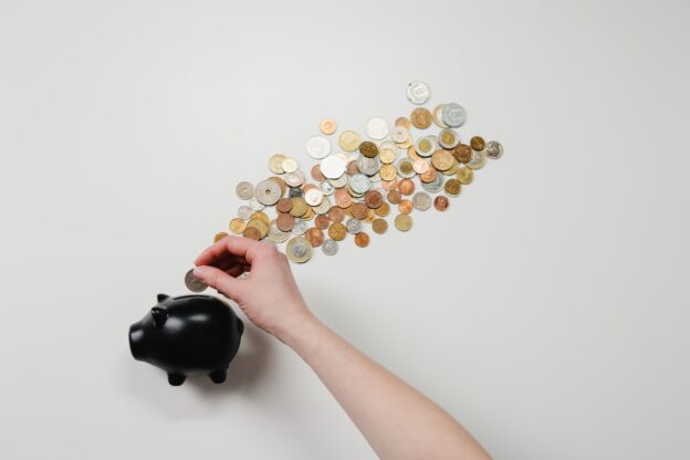 random person putting coins in a piggy bank