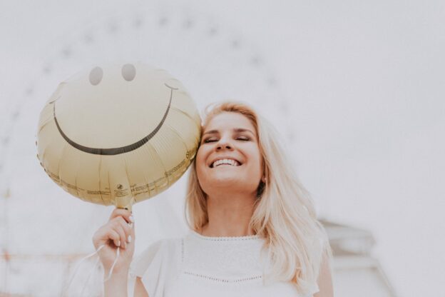smiling woman holding a smiley balloon