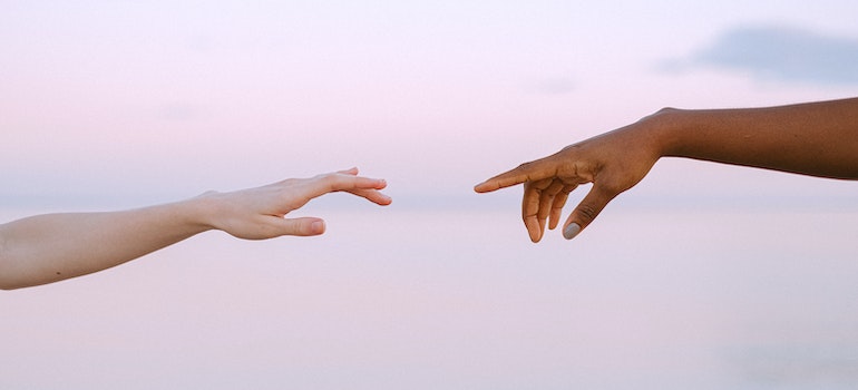 Two hands reaching for each other showing the difference between physical and psychological addiction.