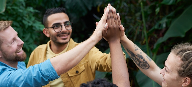 A group of people holding hands and smiling representing the role of emotional wellness in recovery