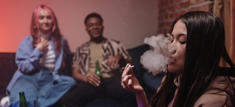 Person smoking marijuana and other people drinking beer as an example of combining alcohol with other drugs