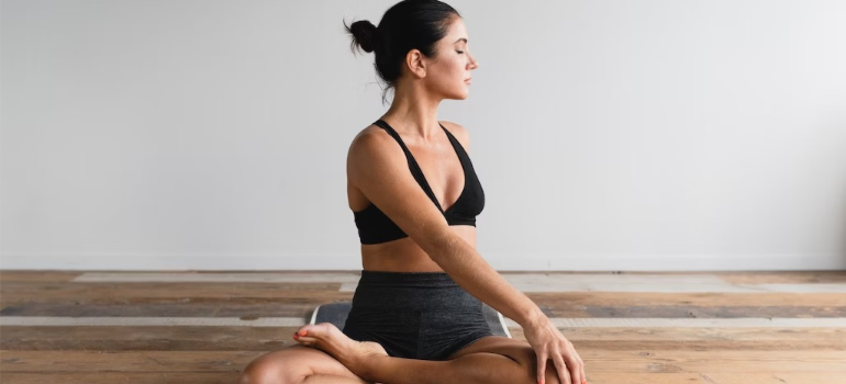 A woman practicing yoga indoors, embracing a holistic approach to recovery that involves alternative therapies for addiction.