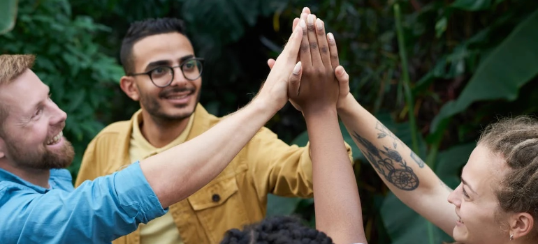 A group of friends joining hands outdoors, illustrating how support groups in addiction treatment help foster bonds.