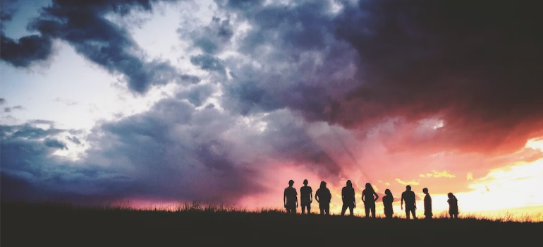 Silhouettes of a group of people on a mountaintop at noon.