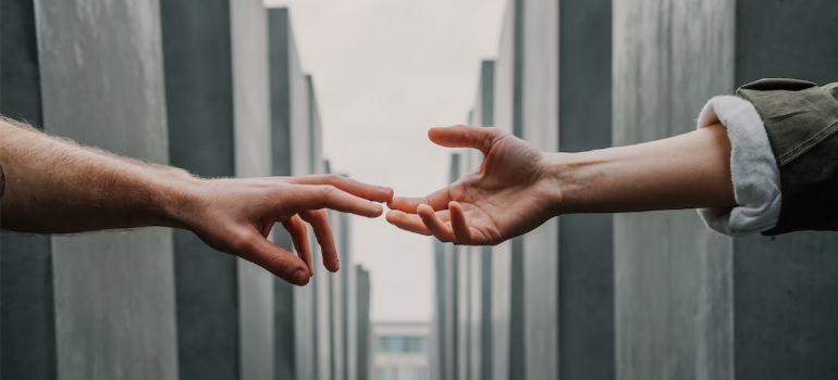 A close-up of two people joining hands outdoors, illustrating the help of support groups in addiction treatment.
