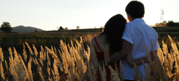 A couple hugging in a field.