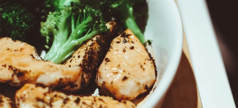 A close-up of a dish with chicken and broccoli.