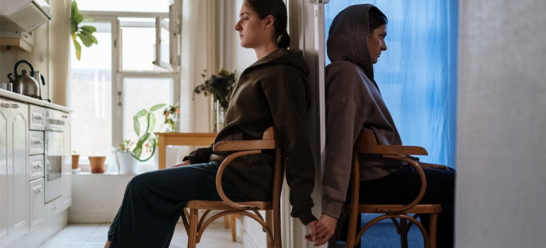 Two sisters holding hands behind a door, illustrating the importance of family support in addiction recovery.