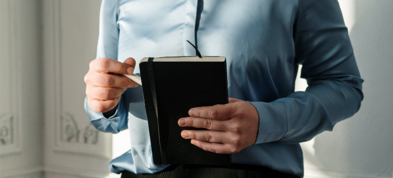 A close-up of an individual holding a notebook.