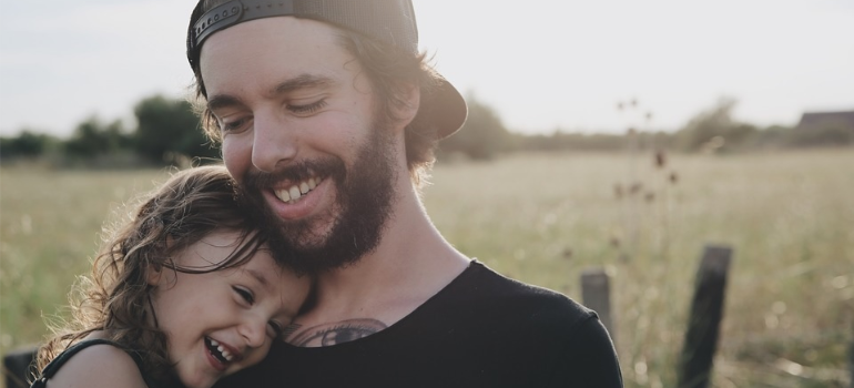 A father hugging his young daughter outdoors.