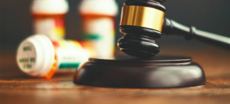 A close-up of a gavel next to drug bottles.