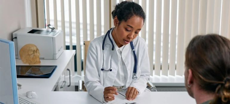 A doctor consulting a patient, illustrating the impact of addiction on West Virginia's economy through increased healthcare costs.