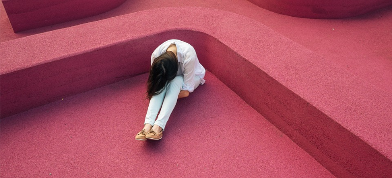 A depressed woman in a curled position, illustrating the psychological impact of the addiction stigma in West Virginia.