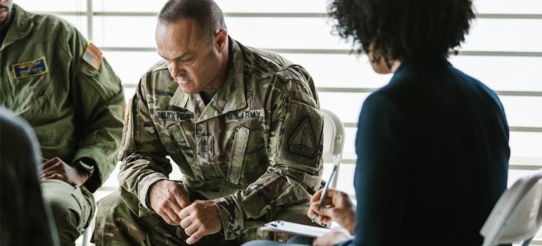 A close-up of a man in military uniform during a group therapy session.