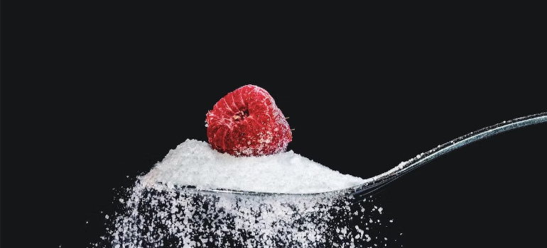 A spoonful of sugar with an earthberry on top, symbolizing the importance of avoiding sugar for nutrition in alcohol addiction treatment.
