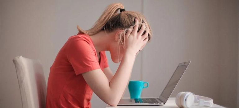 A stressed woman working on a laptop, illustrating that some factors contributing to cocaine abuse require outreach.