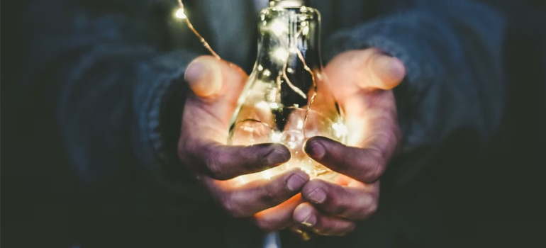 A close-up of a man holding a light bulb.