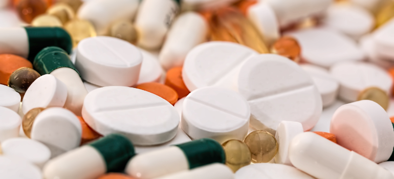A lot of different pills are shown with different sizes and colors. Most are white big, white and round, some are green and some are orange.