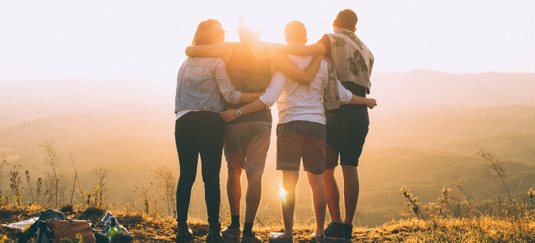 Four people celebrating their recovery milestone with a hike to symbolize why harm reduction is crucial in substance abuse treatment