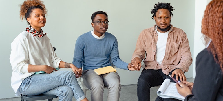 People in group therapy holding hands discussing Ambien addiction withdrawal