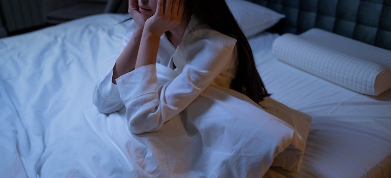 A woman sitting in her bed having trouble sleeping