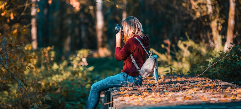 A woman sitting in nature and taking a photo while going through Ambien addiction withdrawal process