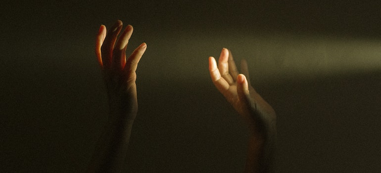 Hands raised to touch a ray of sun