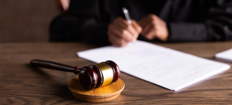 A close-up of a judge writing on paper next to a gavel, illustrating how the effects and dangers of microdosing come with legal considerations.