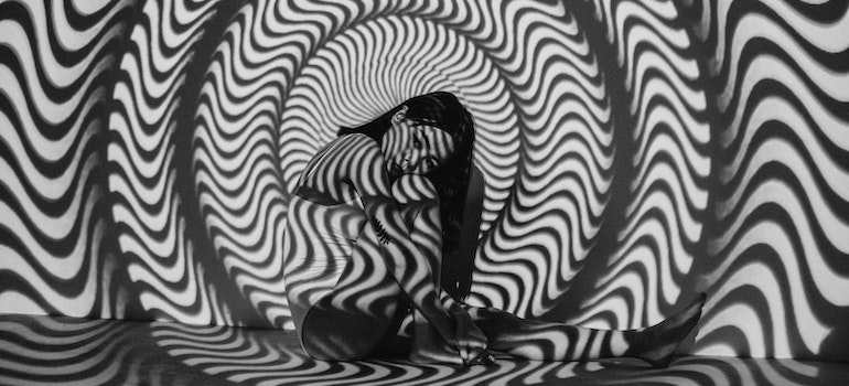 A woman sitting by a wall with a projection on it