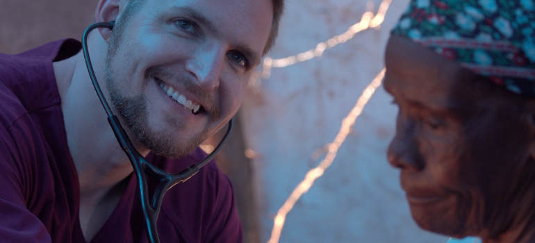 A doctor smiling as he is checking up on a patient.
