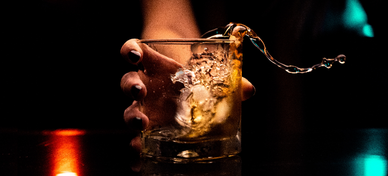 A person holding a glass with alcohol in it.