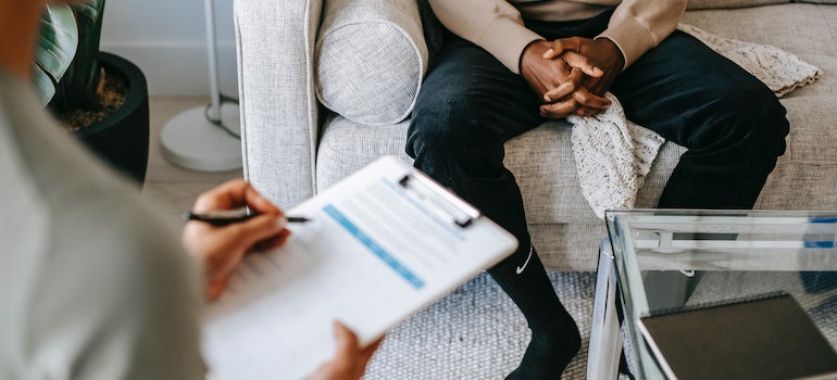 a man in therapy and a therapist taking notes