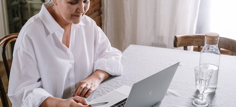 a woman sitting at the table and reading about Types of Substance Abuse Recovery Capital on her laptop