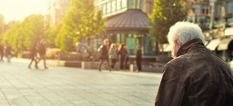 Senior battling addiction is sitting alone on a bench.
