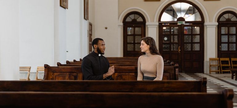 Priest talking to a woman to emphasize the role of churches in overcoming addiction in small-town West Virginia