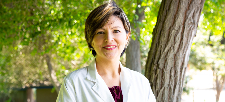 A medical professional is shown, behind her there is nature.