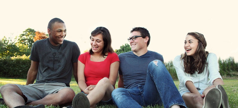 Four students sitting on the grass outside representing the dangers of BORG drinking among WV students