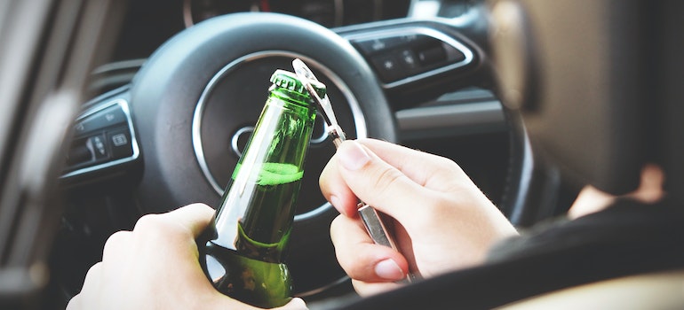 Peron opening a bottle of beer in the car